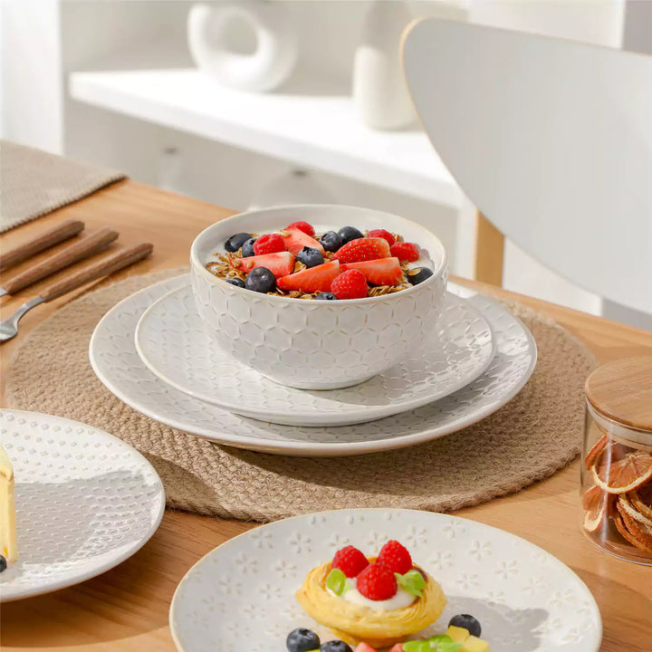 Breakfast parfait layered with yogurt, fresh fruit and granola served in deep cereal bowls on a cozy brunch table