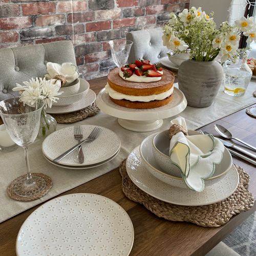 Natural bohemian table setting with stoneware dinnerware, woven placemats, and soft linen napkins