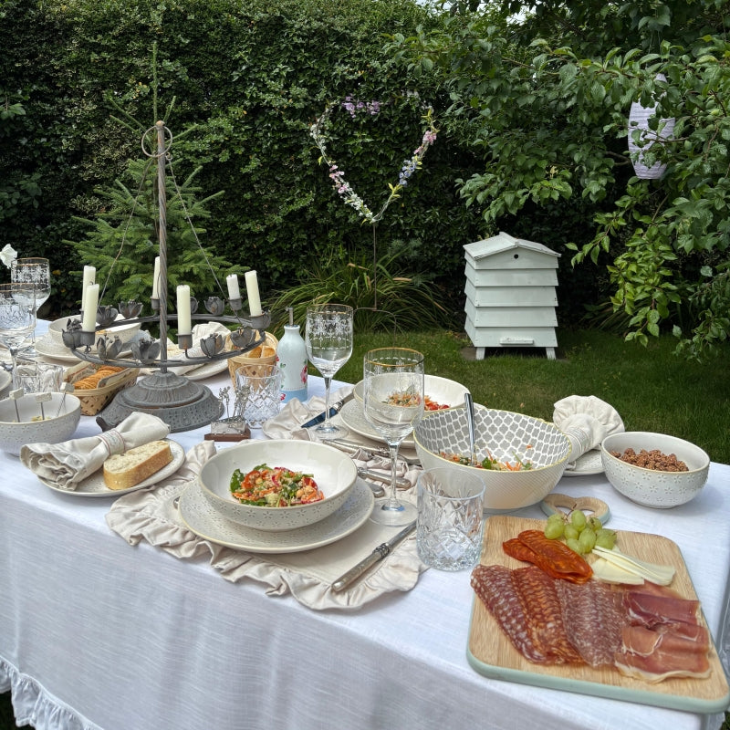 Eco friendly dinnerware arranged on a backyard game day table with reusable ceramic plates, bowls, and serving pieces for BBQ, outdoor dining, and casual entertaining.