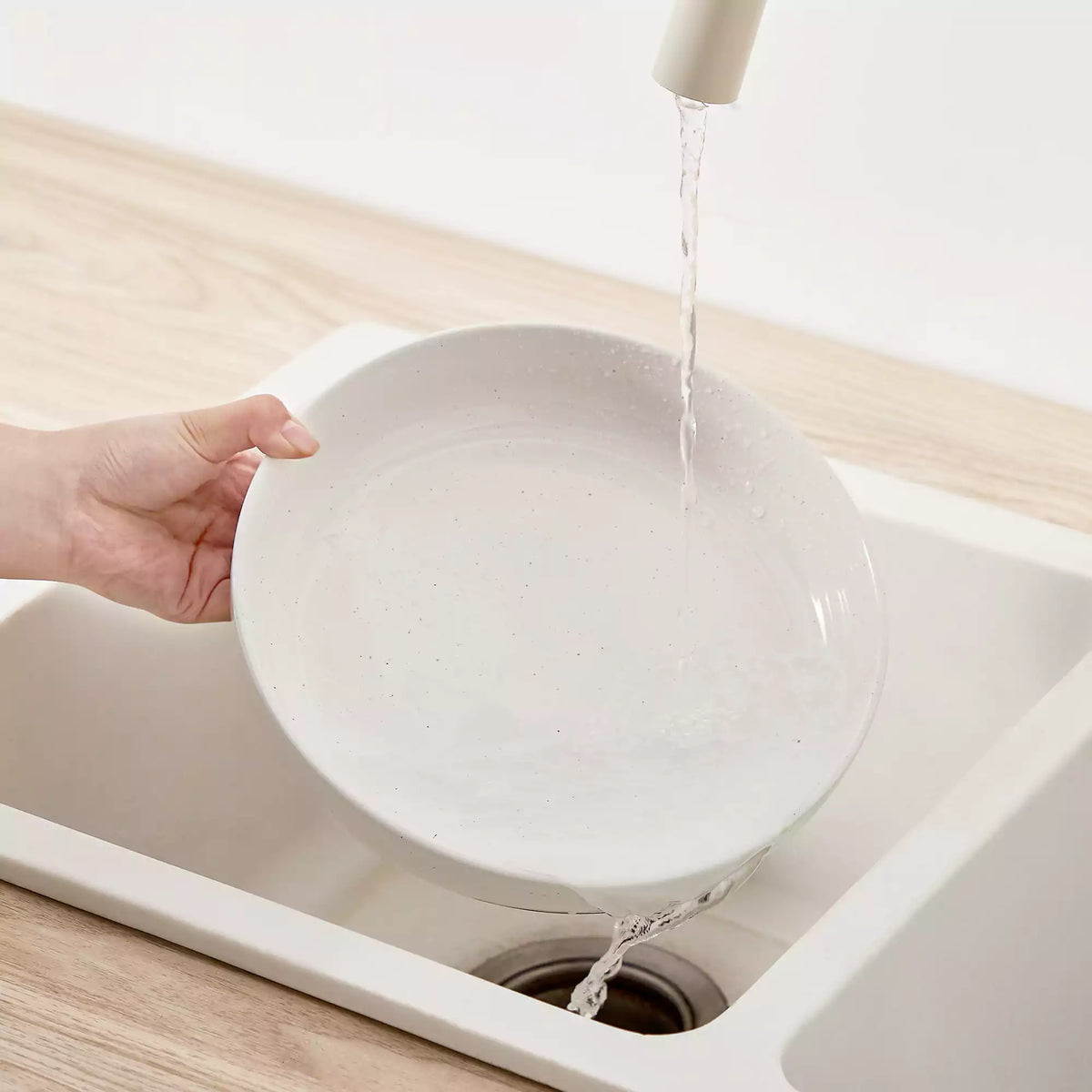 A glossy porcelain plate being easily cleaned after a greasy meal, showing a smooth surface with no oily residue and a clean, bright finish
