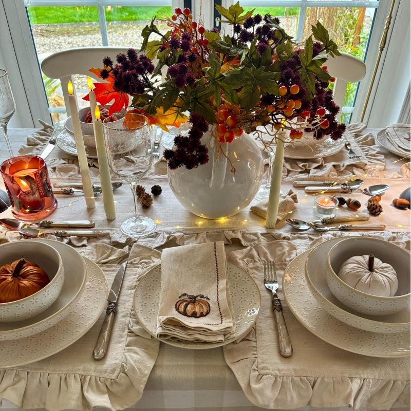 A rustic stoneware dinnerware set displayed on a cozy Halloween table, featuring warm autumn colors and seasonal dishes.