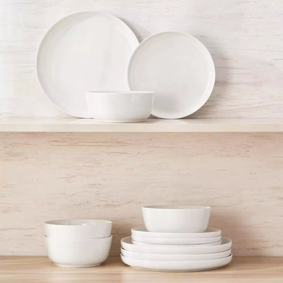 MINA porcelain dinnerware set featuring curved-edge plates and bowls with lifted rims.#color_ivory-white