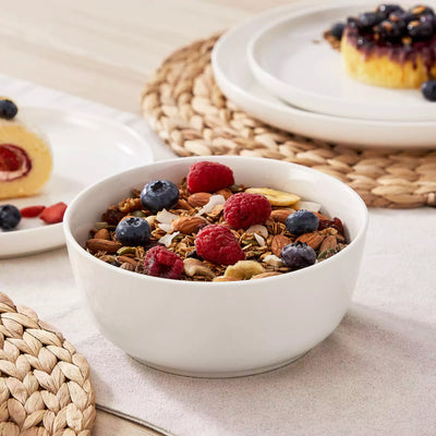 MINA porcelain dinnerware set featuring curved-edge plates and bowls with lifted rims.#color_ivory-white