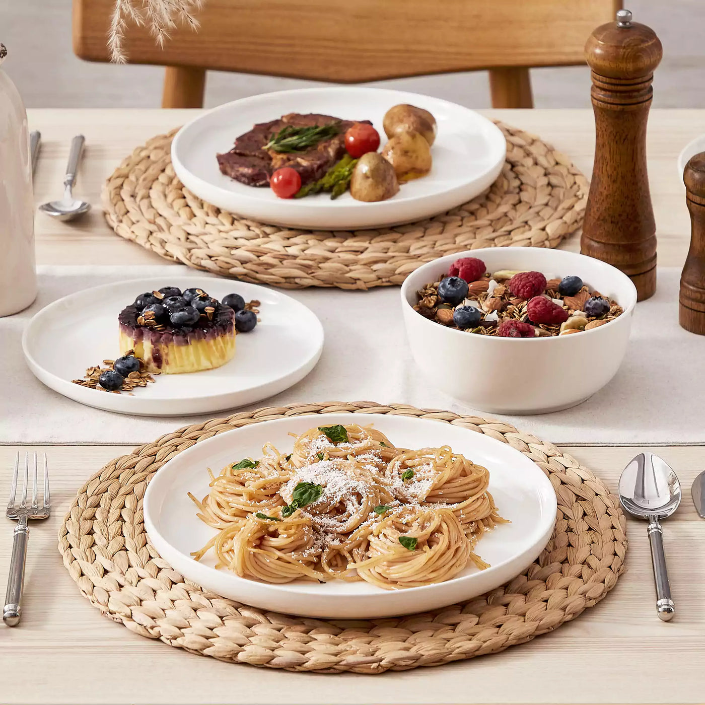 MINA porcelain dinnerware set featuring curved-edge plates and bowls with lifted rims.#color_ivory-white