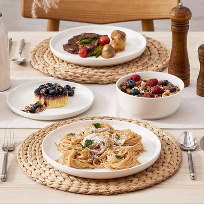 MINA porcelain dinnerware set featuring curved-edge plates and bowls with lifted rims.#color_ivory-white
