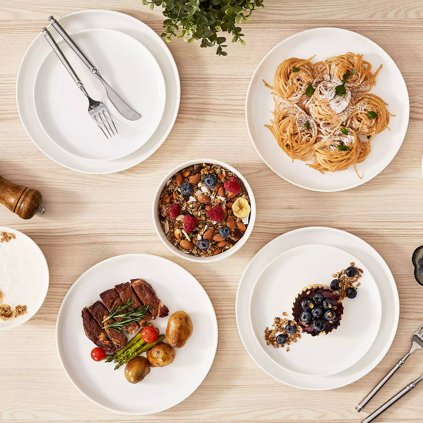 MINA porcelain dinnerware set featuring curved-edge plates and bowls with lifted rims.#color_ivory-white