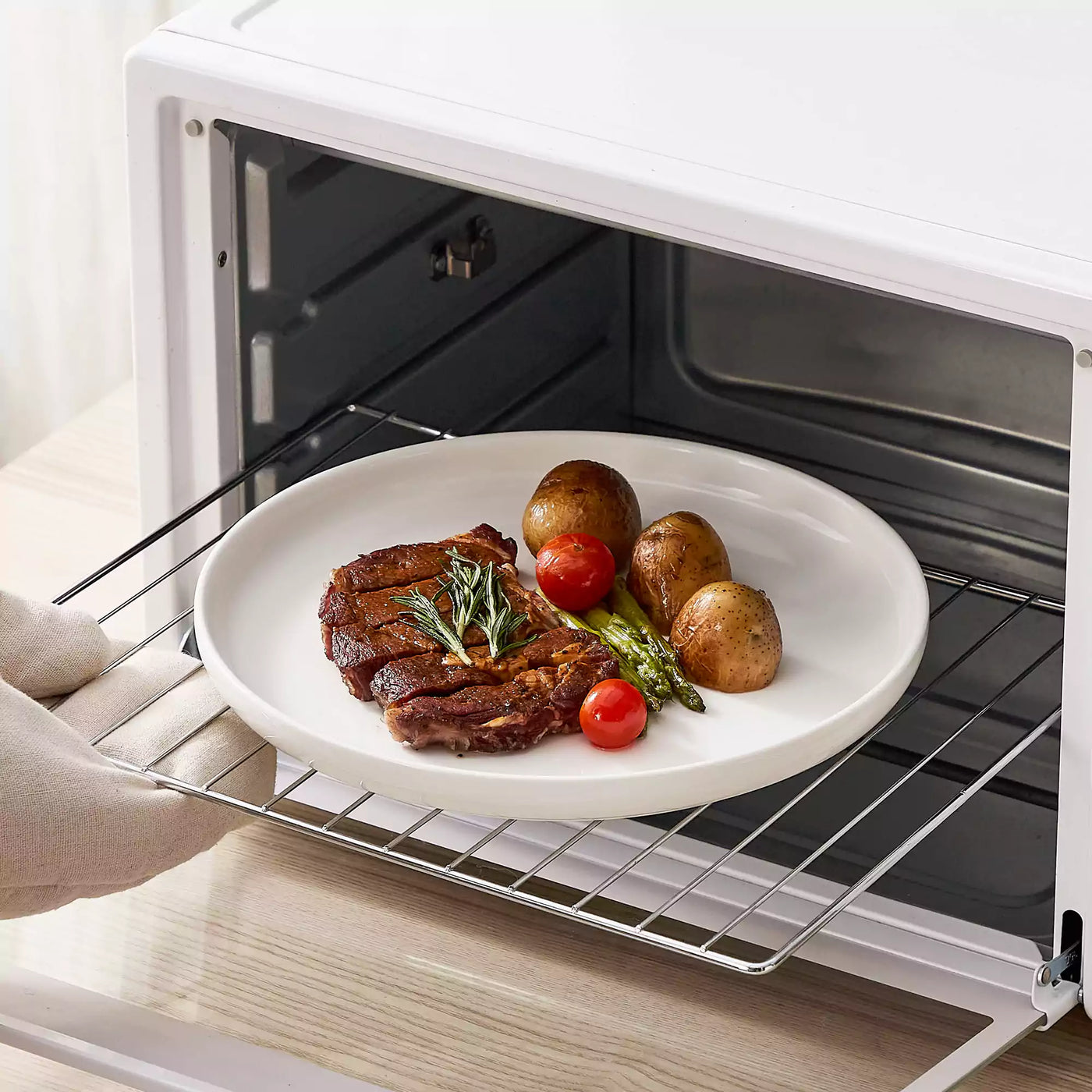 MINA porcelain dinnerware set featuring curved-edge plates and bowls with lifted rims.#color_ivory-white