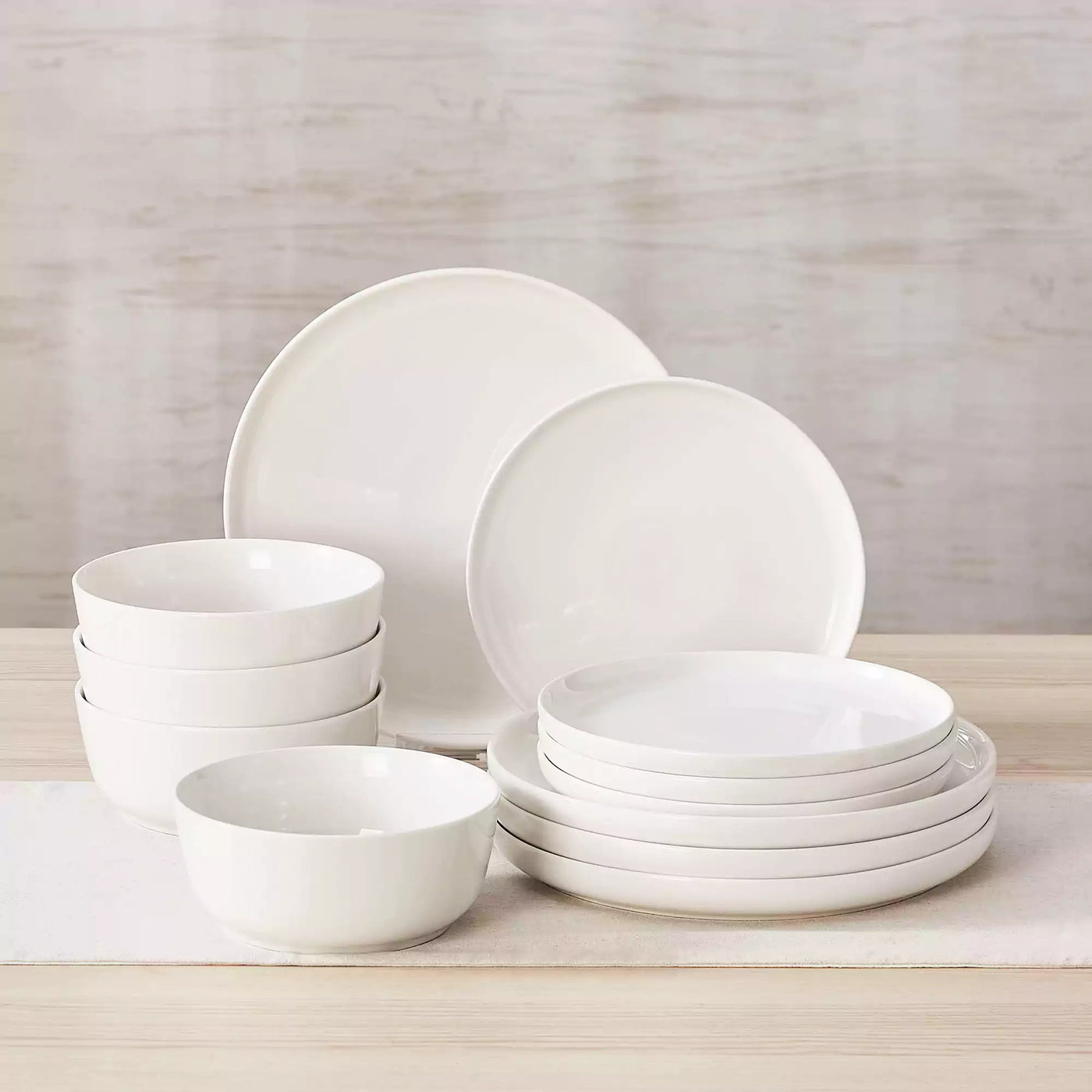 MINA porcelain dinnerware set featuring curved-edge plates and bowls with lifted rims.#color_ivory-white