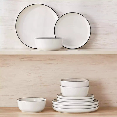 MINA porcelain dinnerware set featuring curved-edge plates and bowls with lifted rims#color_black-trim