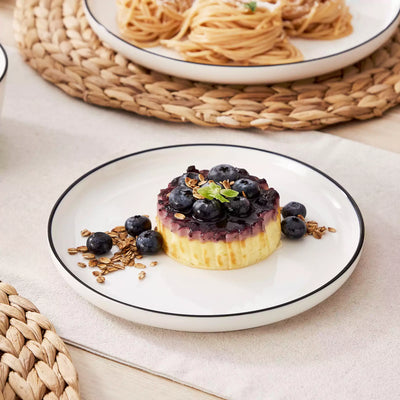 MINA porcelain dinnerware set featuring curved-edge plates and bowls with lifted rims#color_black-trim