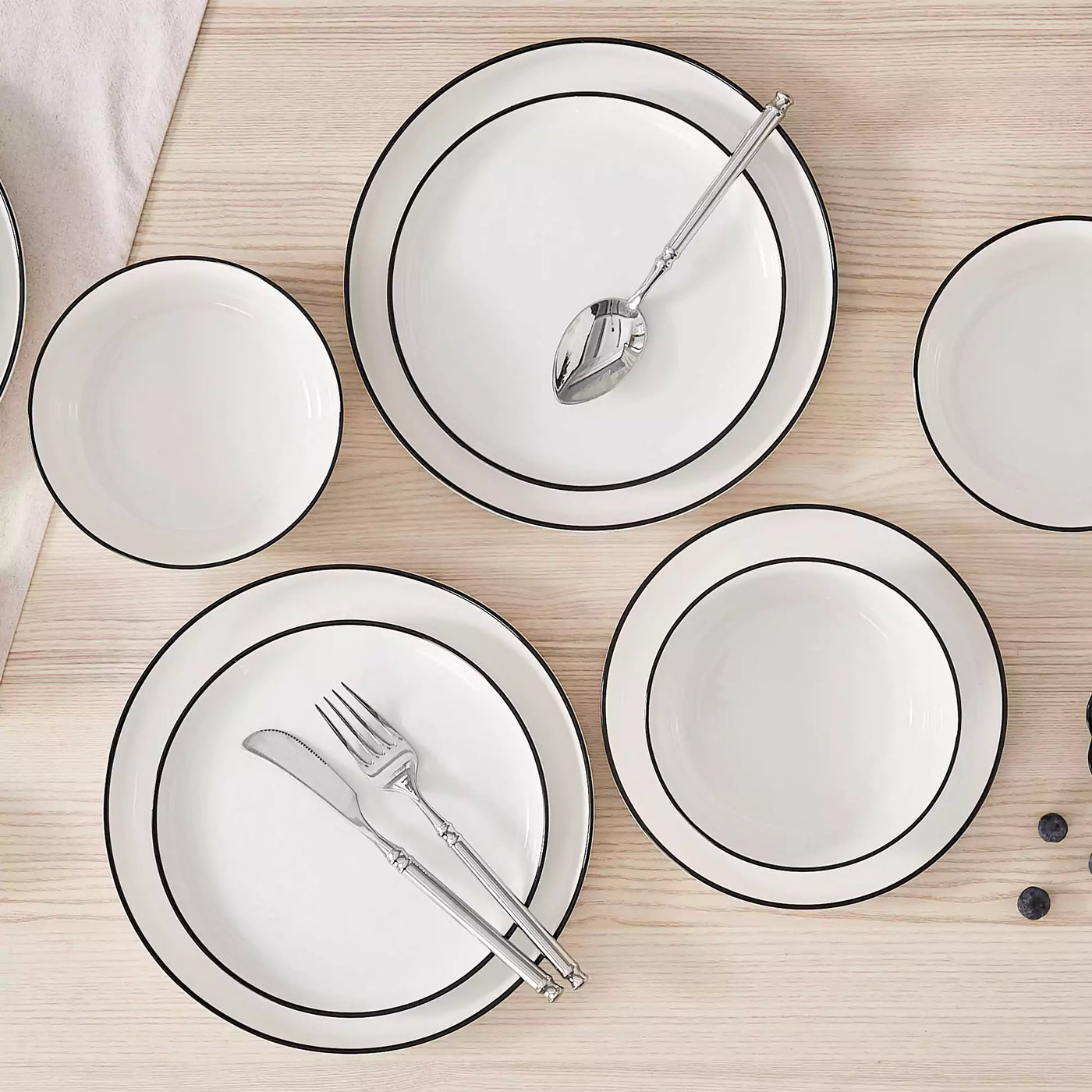 MINA porcelain dinnerware set featuring curved-edge plates and bowls with lifted rims#color_black-trim