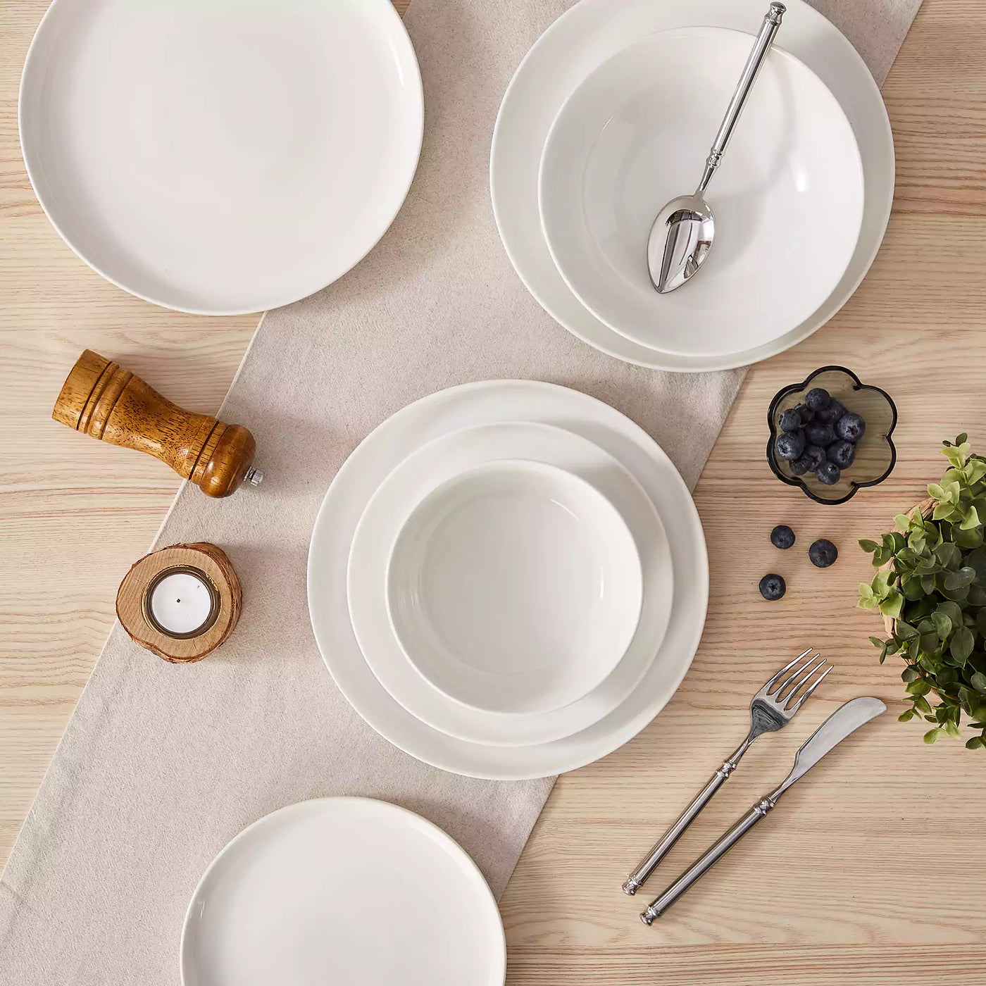 MINA porcelain dinnerware set featuring curved-edge plates and bowls with lifted rims.#color_ivory-white