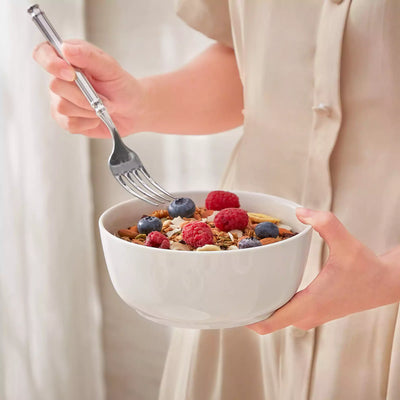 MINA porcelain dinnerware set featuring curved-edge plates and bowls with lifted rims.#color_ivory-white