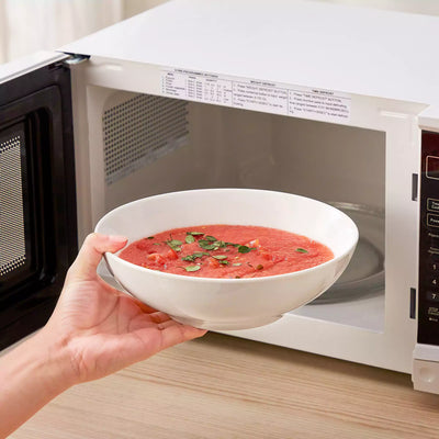 MINA porcelain dinnerware set featuring curved-edge plates and bowls with lifted rims.#color_ivory-white