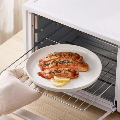 MINA porcelain dinnerware set featuring curved-edge plates and bowls with lifted rims.#color_ivory-white