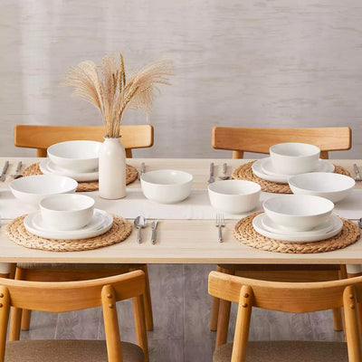 MINA porcelain dinnerware set featuring curved-edge plates and bowls with lifted rims.#color_ivory-white