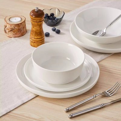 MINA porcelain dinnerware set featuring curved-edge plates and bowls with lifted rims.#color_ivory-white
