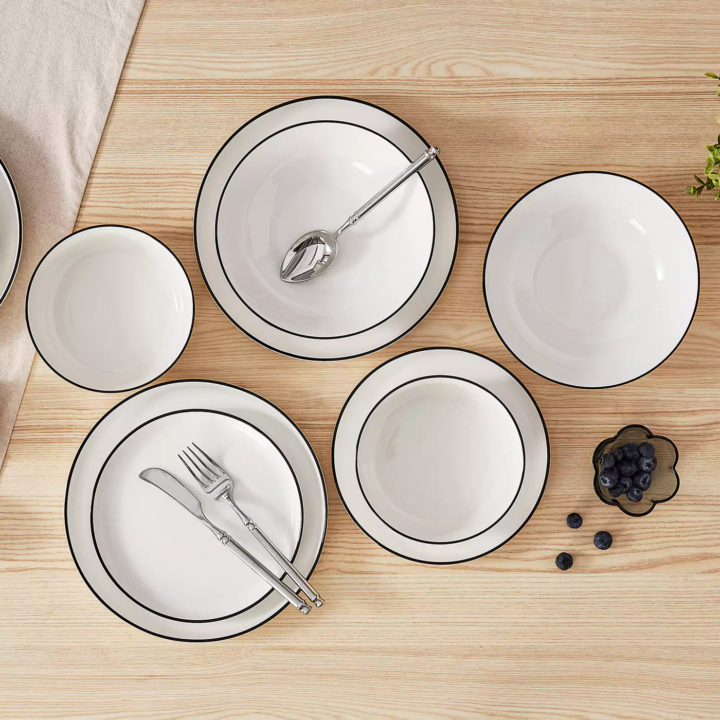 MINA porcelain dinnerware set featuring curved-edge plates and bowls with lifted rims#color_black-trim