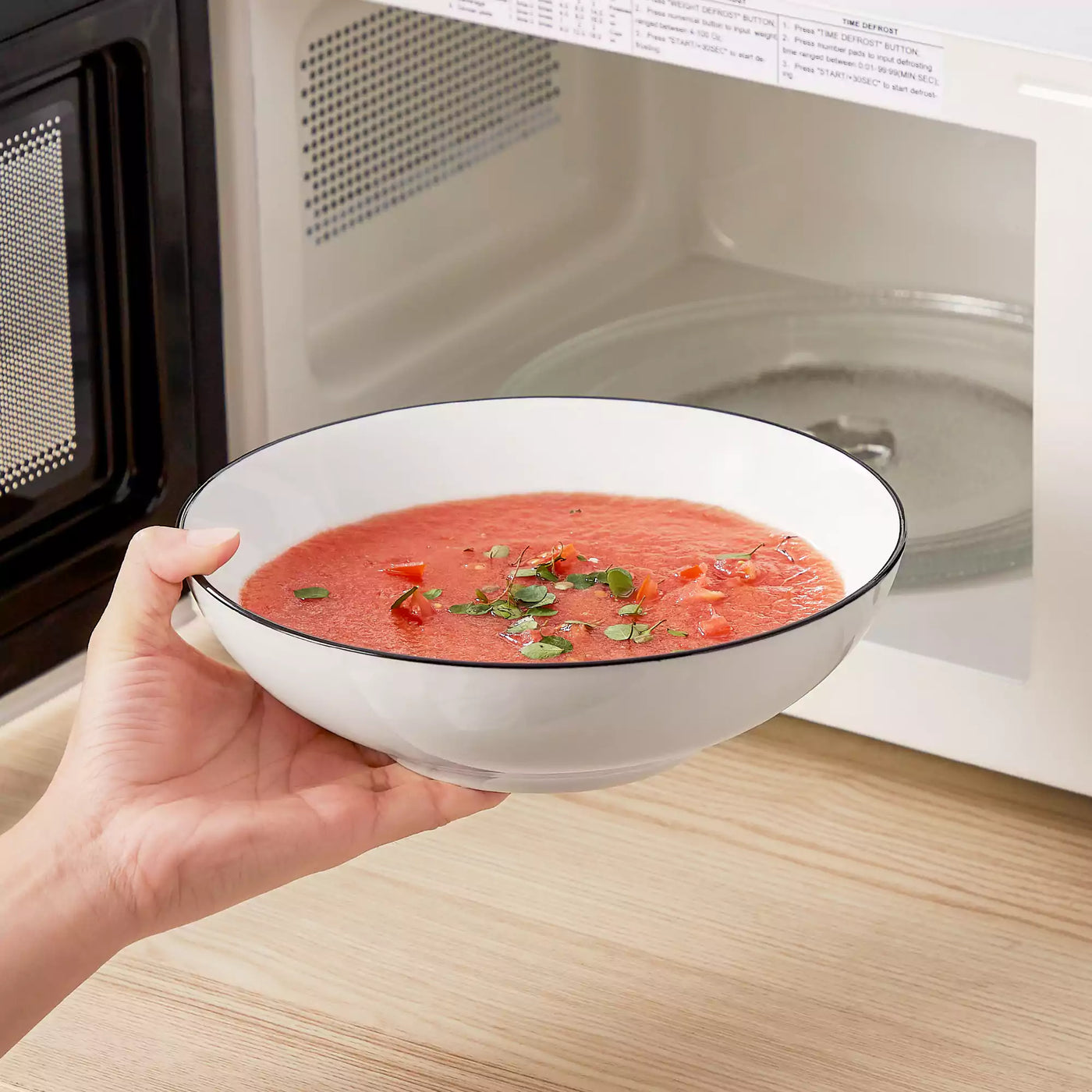 MINA porcelain dinnerware set featuring curved-edge plates and bowls with lifted rims#color_black-trim