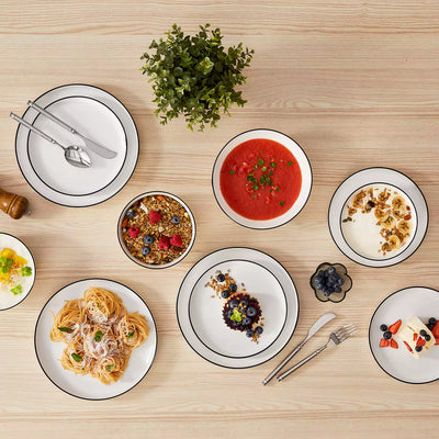 MINA porcelain dinnerware set featuring curved-edge plates and bowls with lifted rims#color_black-trim