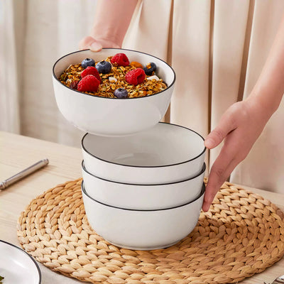 MINA porcelain dinnerware set featuring curved-edge plates and bowls with lifted rims#color_black-trim