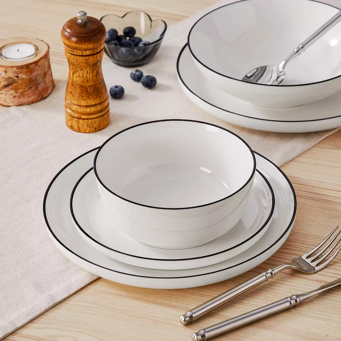 MINA porcelain dinnerware set featuring curved-edge plates and bowls with lifted rims#color_black-trim