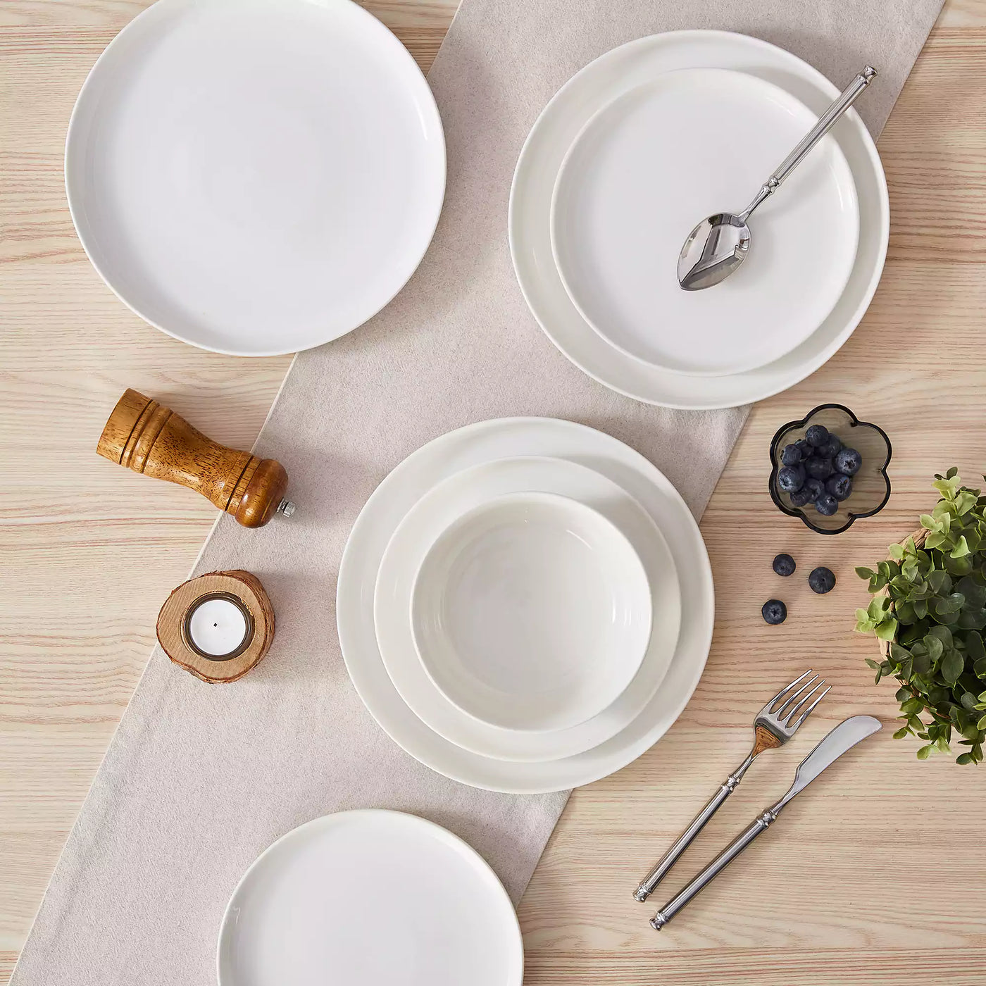 MINA porcelain dinnerware set featuring curved-edge plates and bowls with lifted rims.#color_ivory-white