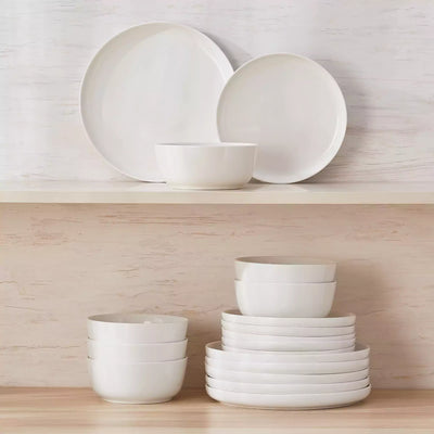 MINA porcelain dinnerware set featuring curved-edge plates and bowls with lifted rims.#color_ivory-white