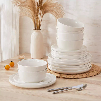 MINA porcelain dinnerware set featuring curved-edge plates and bowls with lifted rims.#color_ivory-white