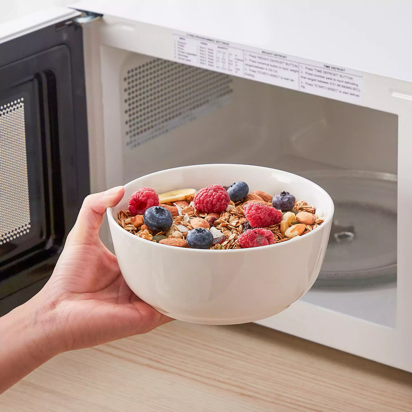 MINA porcelain dinnerware set featuring curved-edge plates and bowls with lifted rims.#color_ivory-white