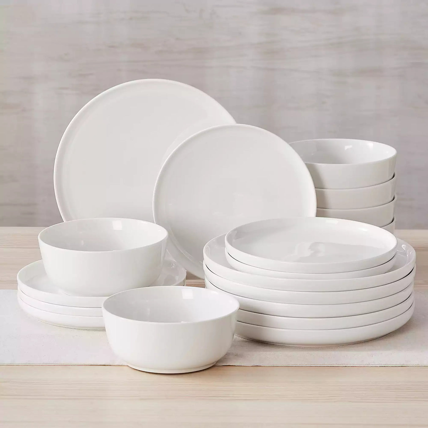MINA porcelain dinnerware set featuring curved-edge plates and bowls with lifted rims.#color_ivory-white