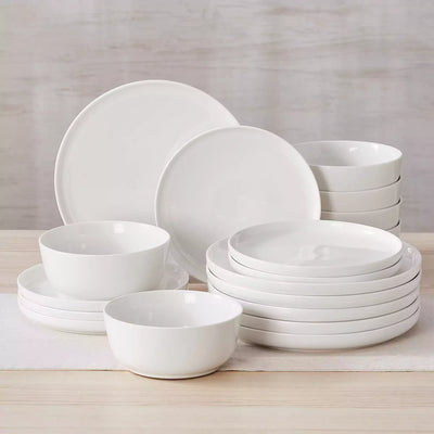 MINA porcelain dinnerware set featuring curved-edge plates and bowls with lifted rims.#color_ivory-white
