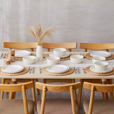 MINA porcelain dinnerware set featuring curved-edge plates and bowls with lifted rims.#color_ivory-white