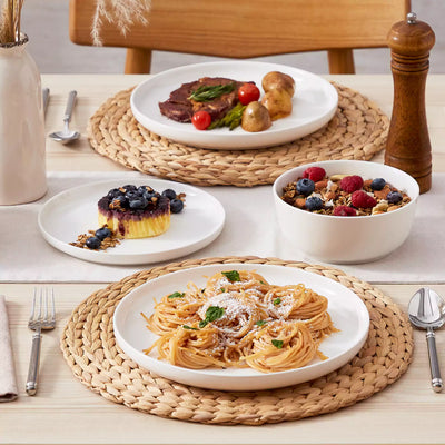 MINA porcelain dinnerware set featuring curved-edge plates and bowls with lifted rims.#color_ivory-white