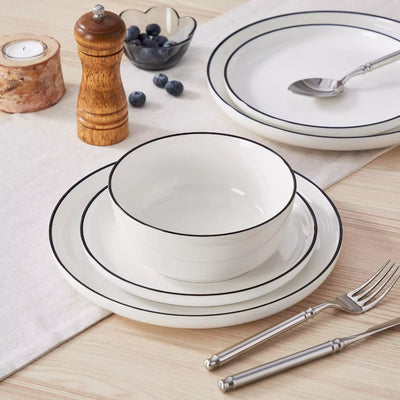 MINA porcelain dinnerware set featuring curved-edge plates and bowls with lifted rims#color_black-trim
