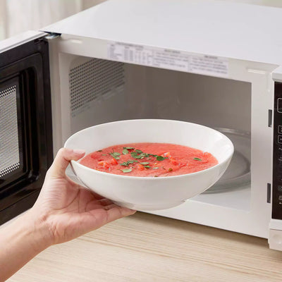 MINA porcelain dinnerware set featuring curved-edge plates and bowls with lifted rims.#color_ivory-white