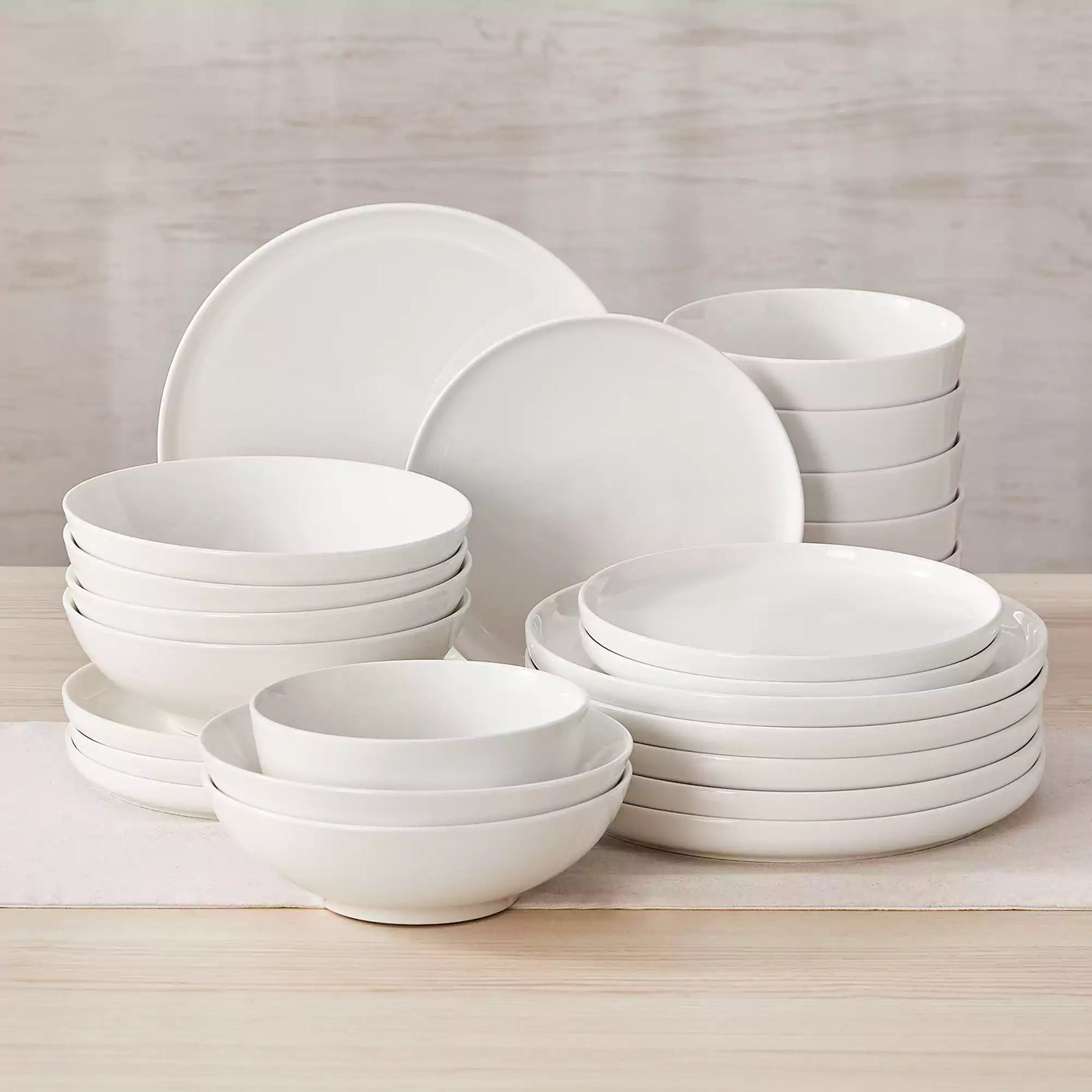 MINA porcelain dinnerware set featuring curved-edge plates and bowls with lifted rims.#color_ivory-white