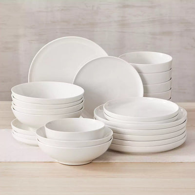 MINA porcelain dinnerware set featuring curved-edge plates and bowls with lifted rims.#color_ivory-white