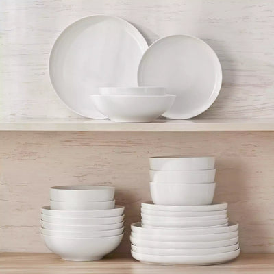 MINA porcelain dinnerware set featuring curved-edge plates and bowls with lifted rims.#color_ivory-white