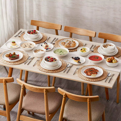 MINA porcelain dinnerware set featuring curved-edge plates and bowls with lifted rims.#color_ivory-white