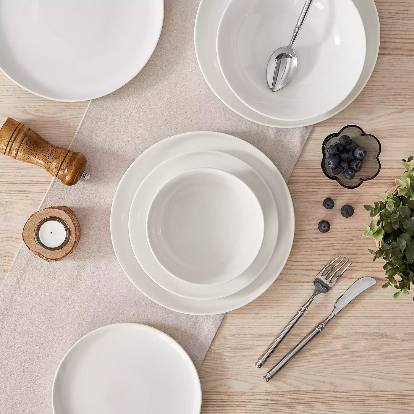 MINA porcelain dinnerware set featuring curved-edge plates and bowls with lifted rims.#color_ivory-white