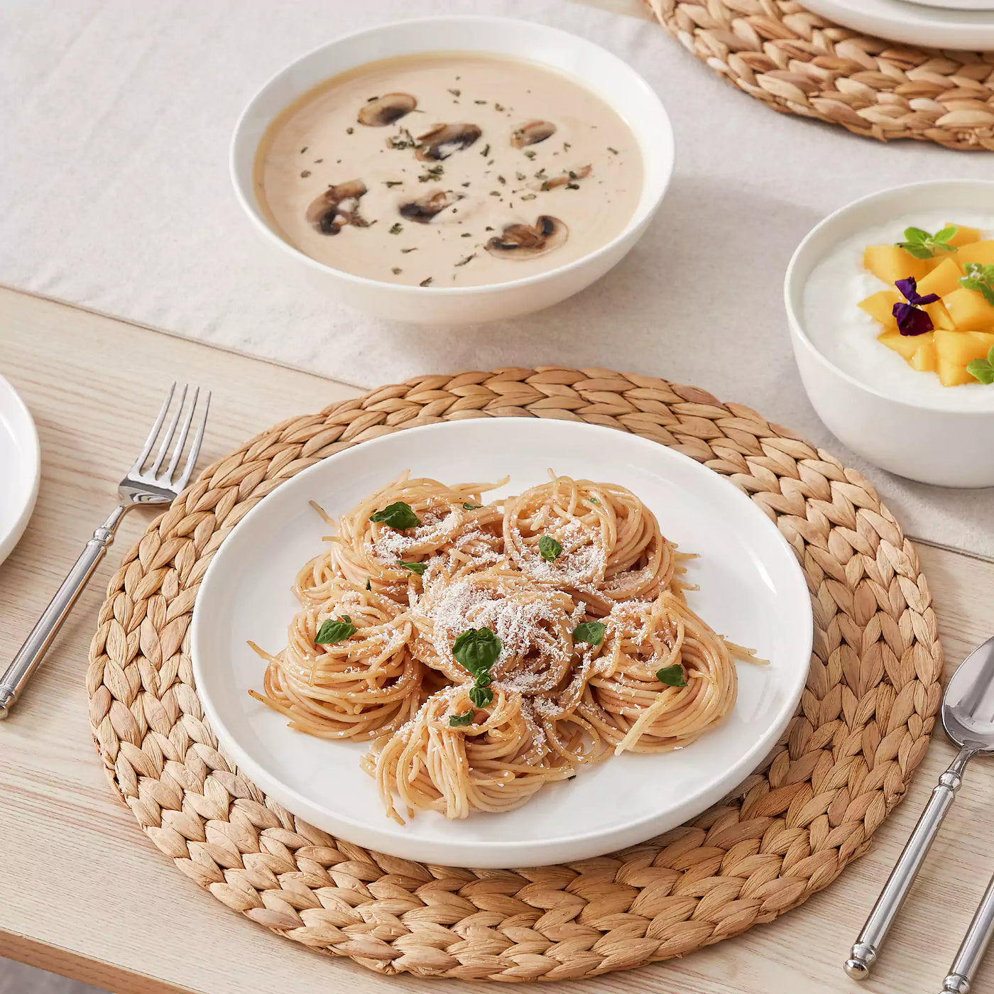 MINA porcelain dinnerware set featuring curved-edge plates and bowls with lifted rims.#color_ivory-white