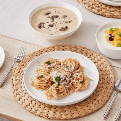 MINA porcelain dinnerware set featuring curved-edge plates and bowls with lifted rims.#color_ivory-white