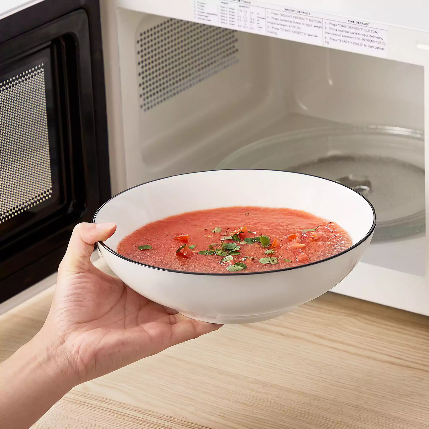 MINA porcelain dinnerware set featuring curved-edge plates and bowls with lifted rims#color_black-trim