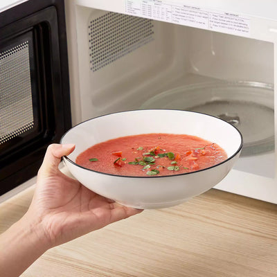 MINA porcelain dinnerware set featuring curved-edge plates and bowls with lifted rims#color_black-trim