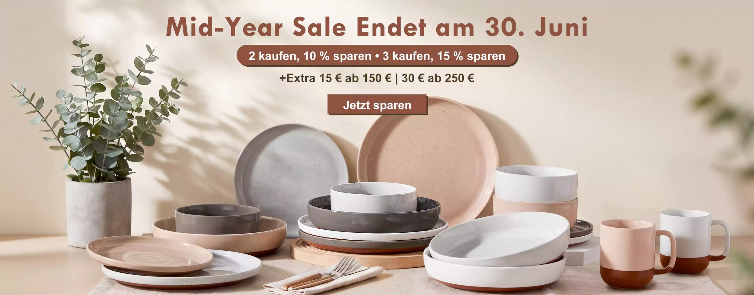 Dining table with ceramic plates and bowls, featuring a mid-year sale advertisement in German.